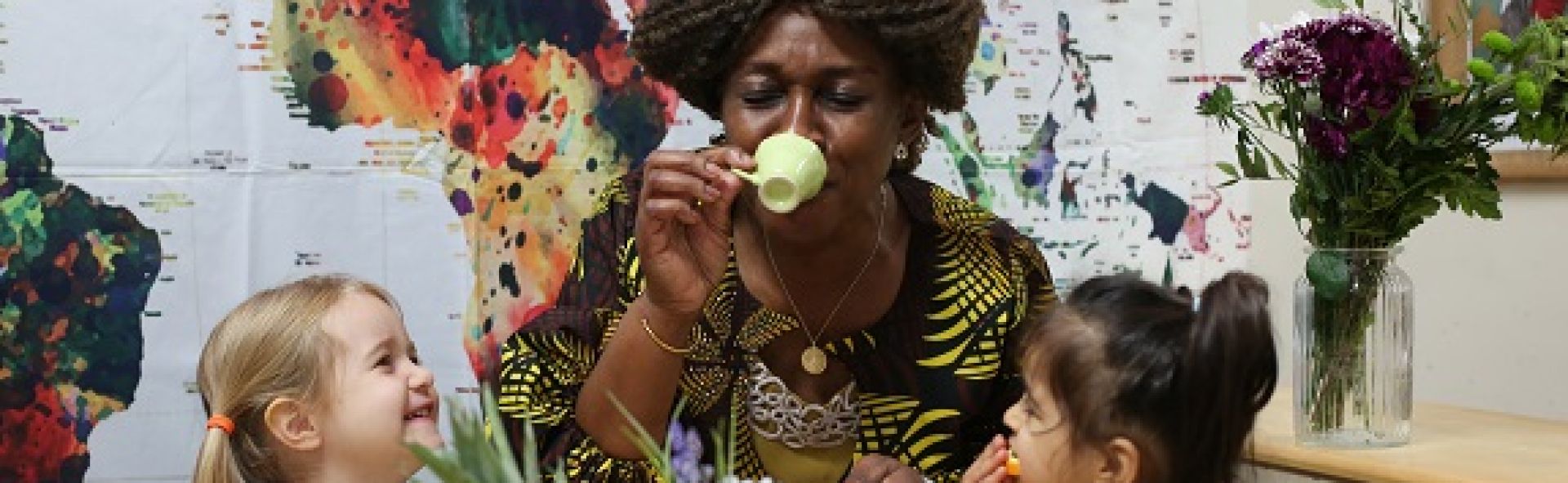 Woman drinks from pretend tea cup with two children