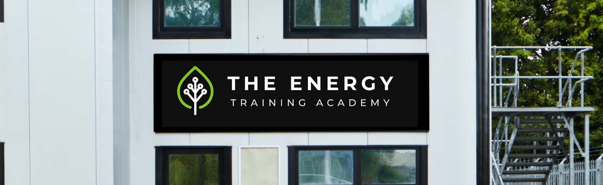 Image of 2 storey white building with black sign and white lettering reading The Energy Training Academy
