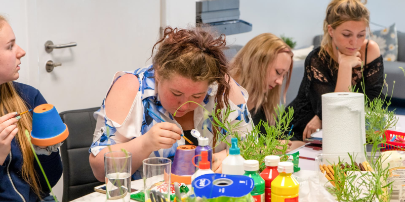 a group of women painting plant pots
